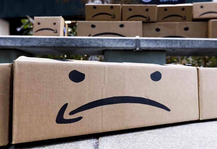 alcuni pacchi di Amazon con il simbolo della freccetta e due puntini neri che fungono da occhi, la freccina è girata al contrario, come segno di tristezza e rabbia