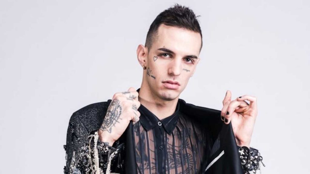 Un big di Sanremo, Achille Lauro con camicia nera trasparente le mani alzte con tanti tatuaggi sulle dita e in faccia