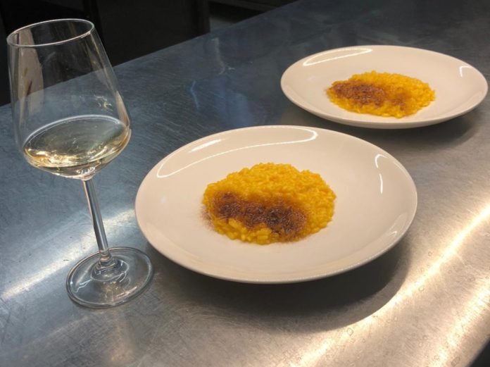 due piatti di risotto preparati dallo chef Luca Pieroni nella sua cucina e un calice di vino bianco