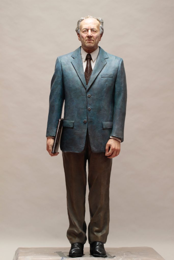 Michele Guaschino, l'artista delle"Meccaniche" interattive. un uomo con vestito blu cmicia bianca e cravatta rossa