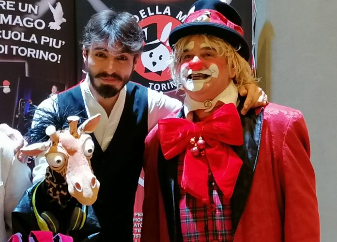 Il ventriloquo Rafael Voltan e la sua giraffina Gi, insieme al clown Arturo, sorridono verso l'obiettivo