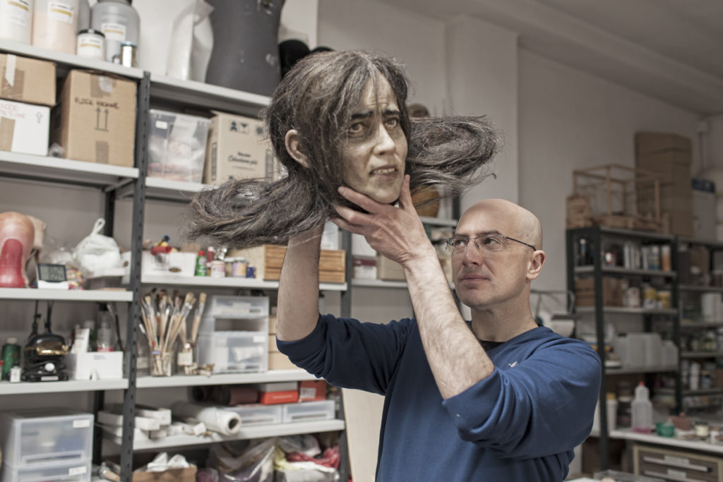Michele Guaschino con una delle. Sue opere presenti nella mostra Meccaniche. Una testa di donna con capelli lunghi
