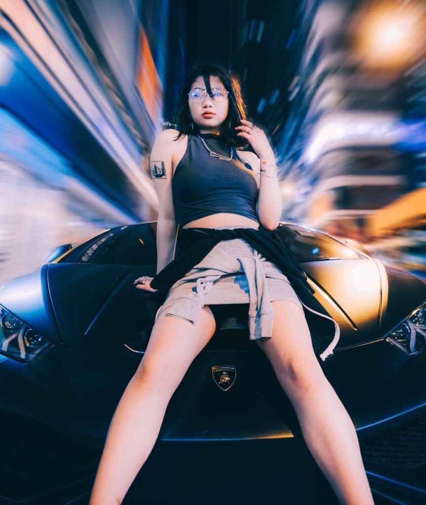 Lamborghini: record di vendite nel 2019. Nella foto una ragazza orientale, appoggiata al cofano di una vettura della casa automobilistica italiana.