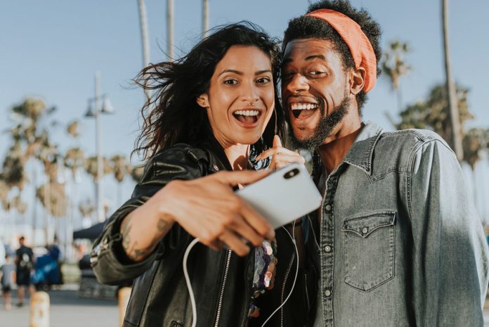 Una ragazza e un ragazzo durante un viaggio in coppia, immortalati mentre si fanno un selfie, con allo sfondo delle altissime palme