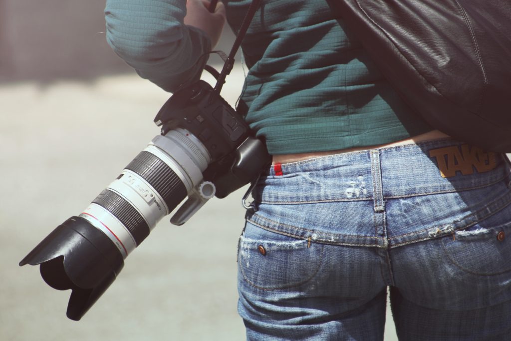 La dura vita di un reporter: primo piano del fondoschien di una fotografa con la camera a tracolla