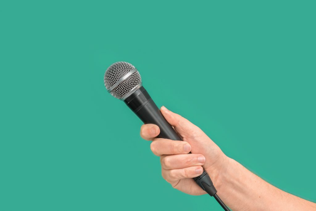 La dura vita del reporter: primo piano di una mano che impugna un microfono
