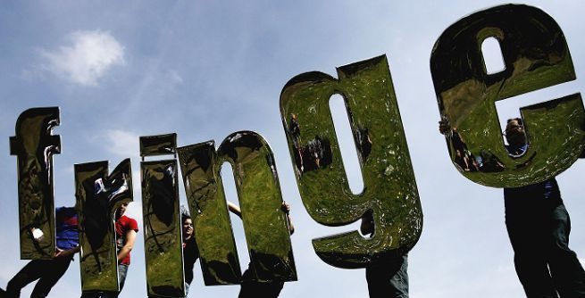 fringe festival, 6 vincitori, come le 6 lettere della parola fringe, scritta fringe stampata in 3D, sei persone tengono una lettera ciascuno, nascoste dietro le lettere che rispecchiano il verde di una valle verde
