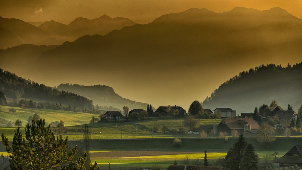 paura degli spazi troppo aperti, paesaggio di campagna in uno spazio aperto, ci sono alberi, qualche casetta in mezzo alla foto, e una catena di montagne sullo sfondo