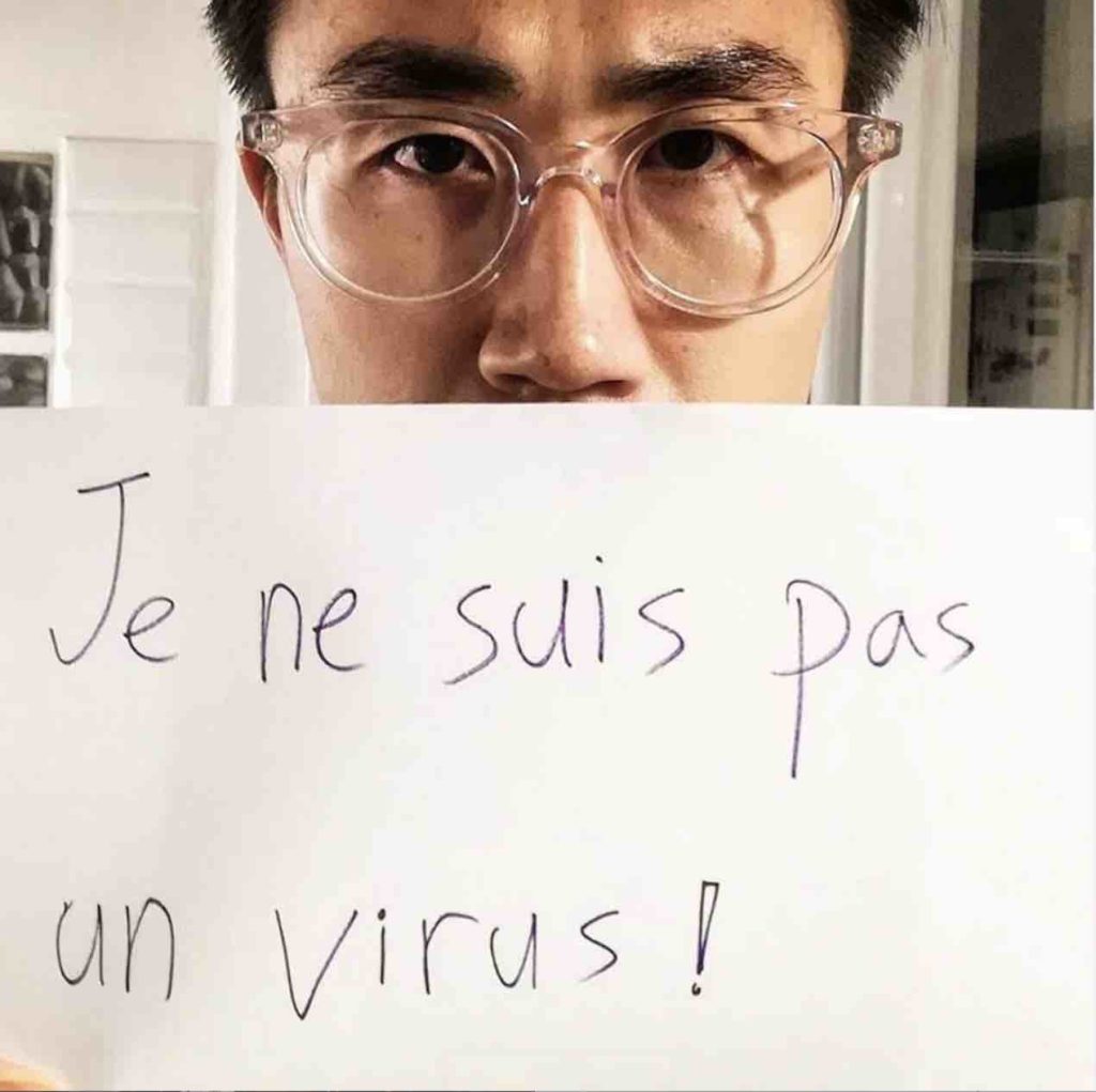 Covid-19 il coronavirus un cinese tiene davanti al viso con gli occhi scoperti un foglio con scritto je ne suis pas un virus