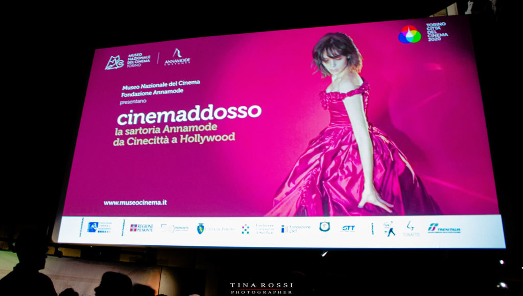 la locandina di cinemaddosso su sfondo fucsia una donna con un vestito rosso ampio e lungo 