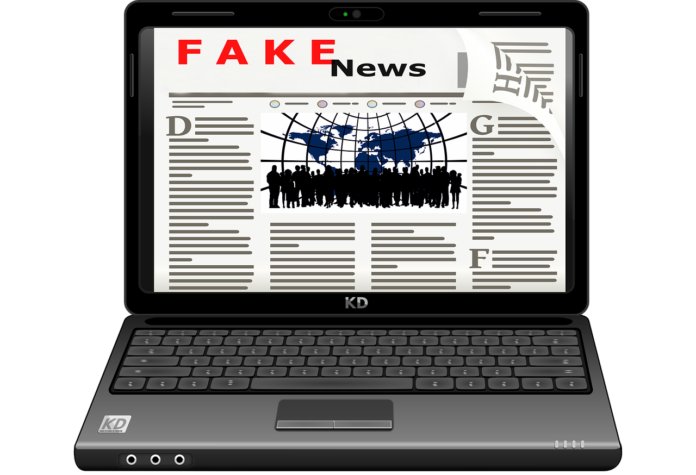 virus e fake news #siateresponsabili un computer con lo schermo aperto on la videata su un giornale fake news