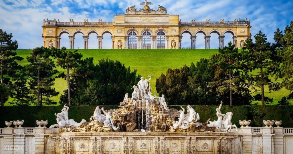Il nostro tour virtuale al Castello di Schönbrunn prevede anche una visita all'esterno. Vista dal pendio, con la fontana di Nettuno in primo piano e il Castello sullo sfondo.