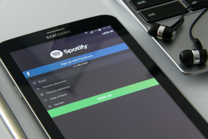 Quarantena in musica, andrà tutto bene. Un telefonino accesso sull'applicazione Spotify e due auricolari a fianco