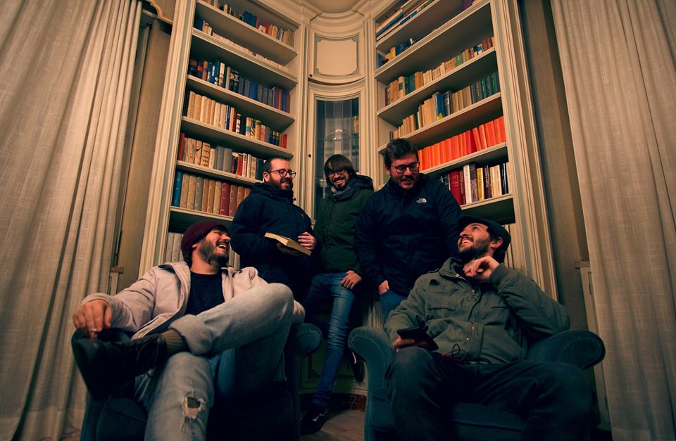 Under The Bed, fuori il nuovo EP “Controlled Filth” la foto ritrae i 5 membri della band con alle spalle una libreria