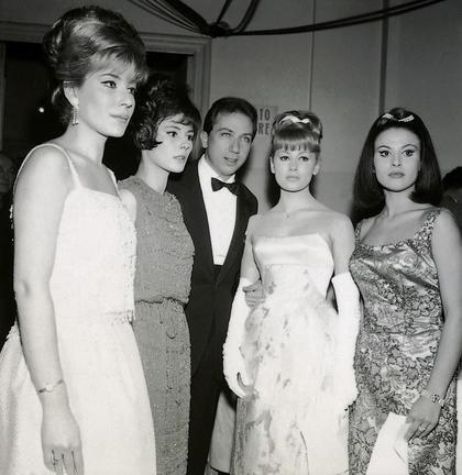 I conduttori di #Sanremo1963. Mike Bongiorno è al centro con le vallette. Foto in bianco e nero. Tutte le donne hanno abiti lunghi ed eleganti e acconciature curate.