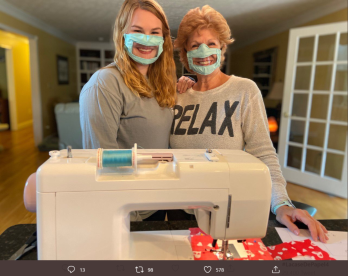 Mascherina trasparente, sordi. Ashley Lawrence e sua mamma si abbracciano. Indossano entrambe la mascherina trasparente per poter far vedere le labbra. Davanti a loro c'è una macchina da cucire bianca.