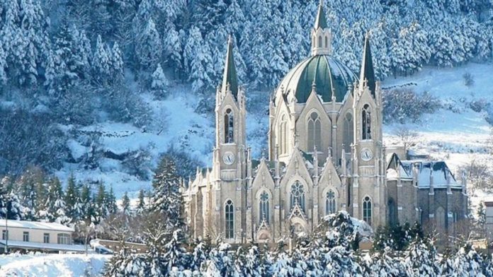 Castelpetroso, borgo, santuario. Il paesaggio è innevato e vede in primo piano il Santuario simbolo del borgo di Castelpetroso. E' di colore bianco ed alcuni particolari di colore verde scuro.