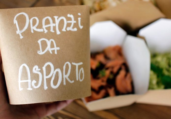 Torino apre take away il cartello pranzo da asporto e sullo sfondo dei sacchetti con del cibo