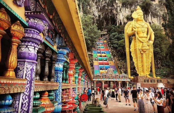Destinazione Malesia: Tour virtuale alle Grotte di Batu. nella foto l'ingresso diella grotta principale con un porticato con colonne colrate e una statua indiana dorata