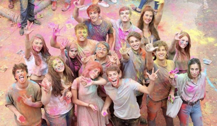 Nella foto i personaggi di Skam Italia 3, inquadrati dall'alto. Tutti sorridenti con le braccia al cielo e colorati delle tinte dell'arcobaleno a una festa