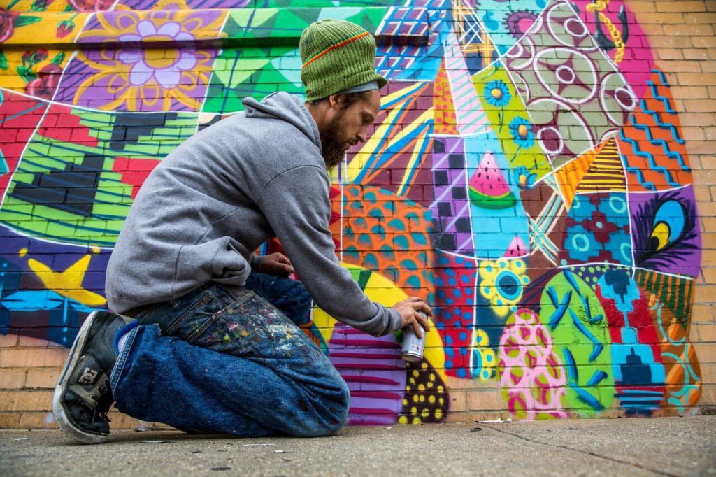 Louis Masai street artist mentre pittura su un muro