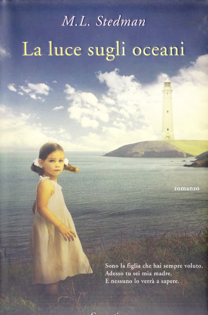 copertina del libro la luce sugli oceani di Stedman, una bambina che indossa un vestitino lungo bianco, con i codini, girata di profilo verso l'oceano e il faro 