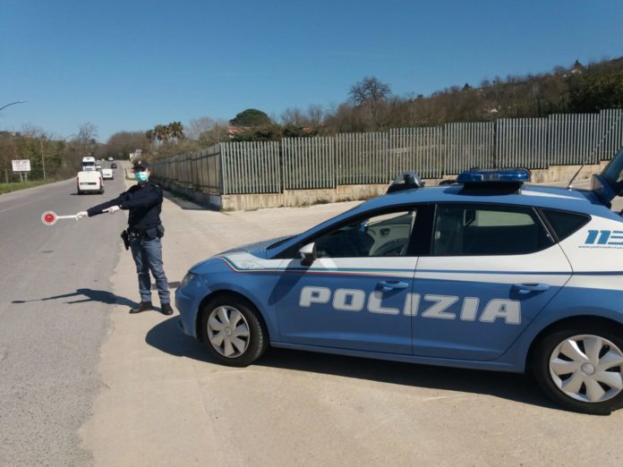 Multe e controlli la polizia dice basta nella foto una volante con un poliziotto con mascherina che ferma con la paletta rossa