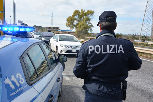 Polizia contro Conte per permessi disabili - nella foto un poliziotto di schiena con la divisa affianco all'auto della polizia