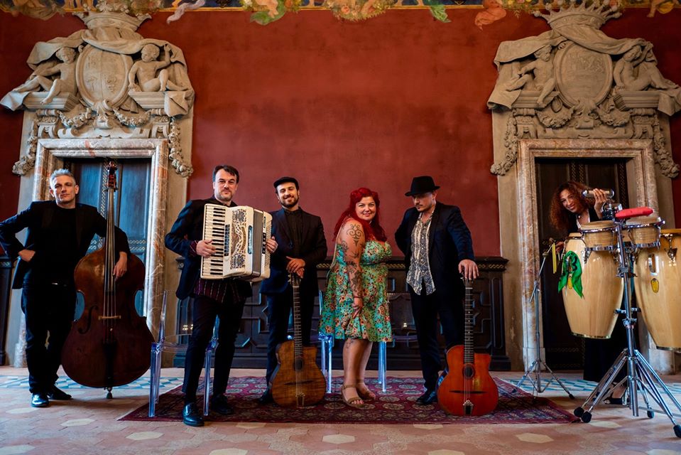 “Non dire una parola” di Clan zingaro. nella foto la band al completo, ritratta in una stanza dall'architettura barocca, sullo sfondo un muro rosso scuro