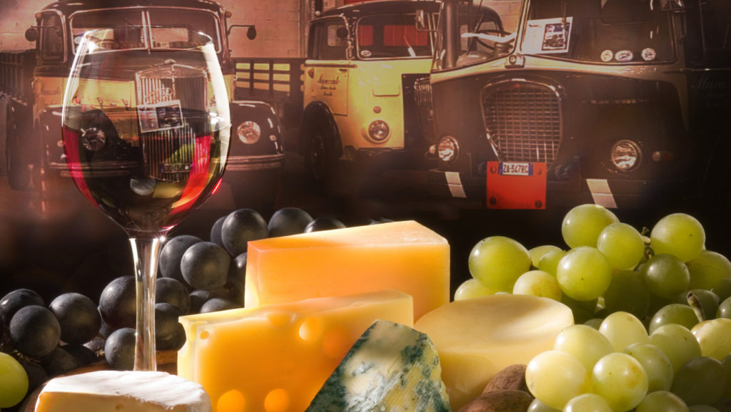 Sapori e Motori alla Serra - nella foto un bicchiere con del vino rosso, del formaggio, dell'uva e sullo sfondo dei mezzi storici