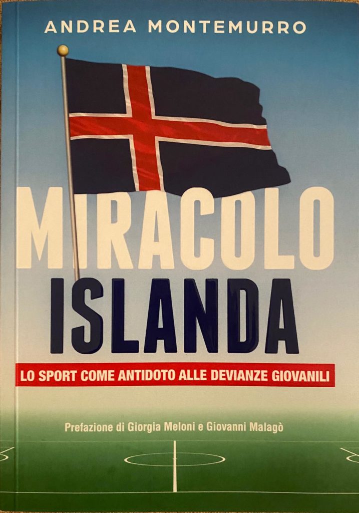 Nella foto la copertina del libro "Miracolo islanda" con la bandiera islandese, sotto il titolo. La parola "miracolo" è grande in bianco" mentre "Islanda" è blu. Poi il sottotitolo in rosso, al di sotto lo sfondo di un campo sportivo.
