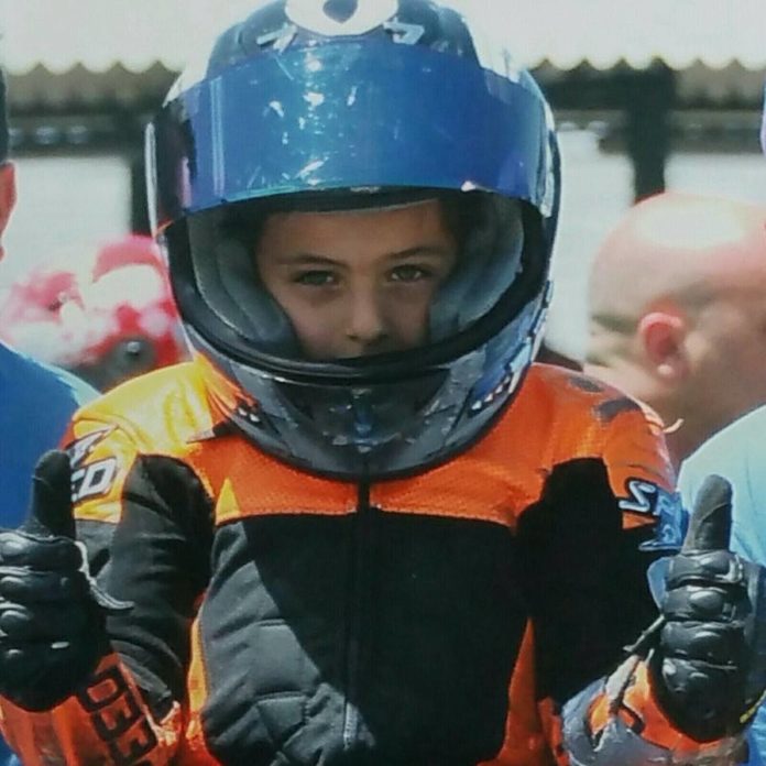 Talento di Flavio Piccolo 777. nella foto il giovanissimo pilota romano, che indossa un casco integrale nero, una tuta nero e arancio e alza entrambi i pollici.