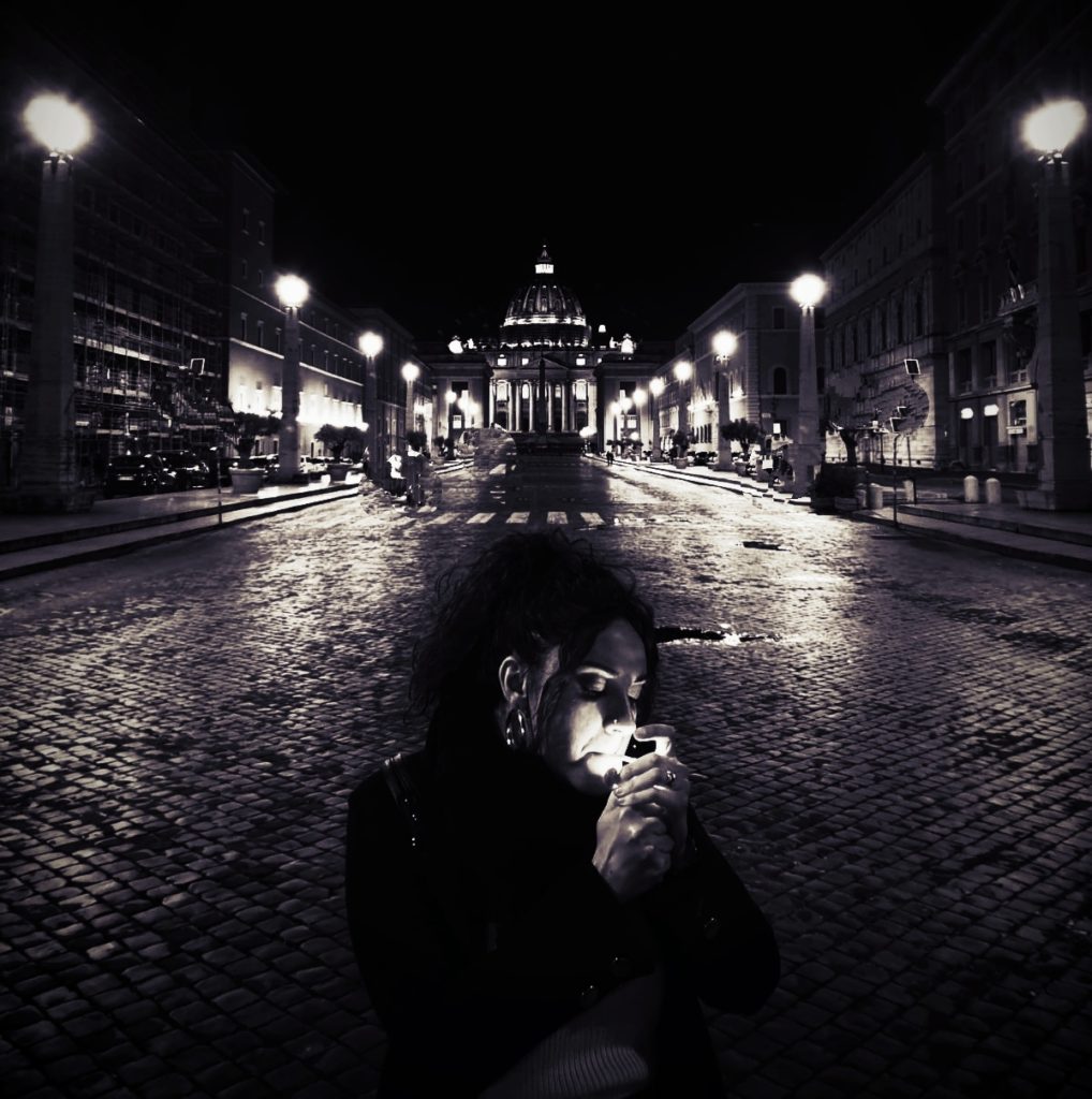 Nicole Riso Donna Roma. Nella foto in bianco e nero, la cantante intenta ad accendere una sigaretta. Sullo sfondo via della conciliazione e la basilica di san pietro