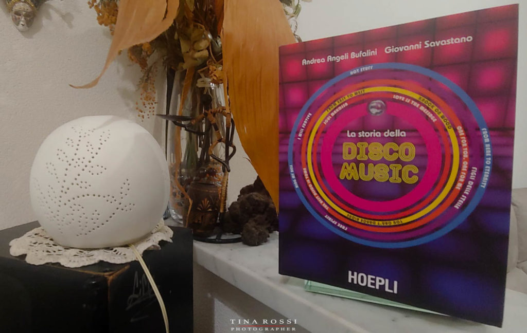 la storia della disco music il libro appoggiato in piedi vicino ad un vaso di fiori e a una palla illuminata