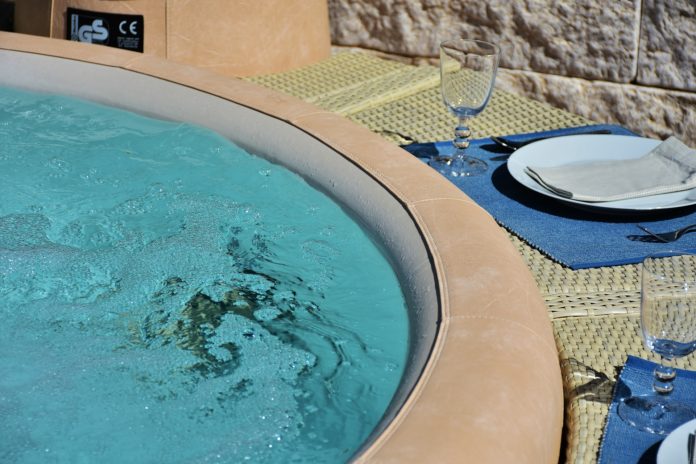RelaxingEm di Emilio una vasca idromassaggio e un bicchiere con un piatto sul bordo piscina