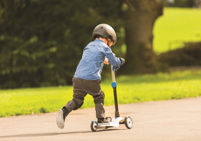 bici e monopattino nella foto un bimbo corre con il suo monopattino e il casco in testa