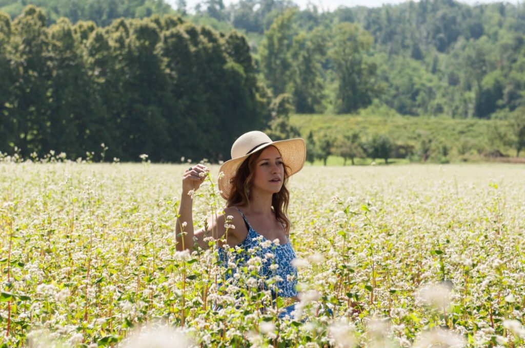barbara monte "Il sud/le sud" nella foto la cantante e violinista, in un campo di di fiori, con un cappello largo di paglia e un vestito azzurro. Sullo sfondo un bosco