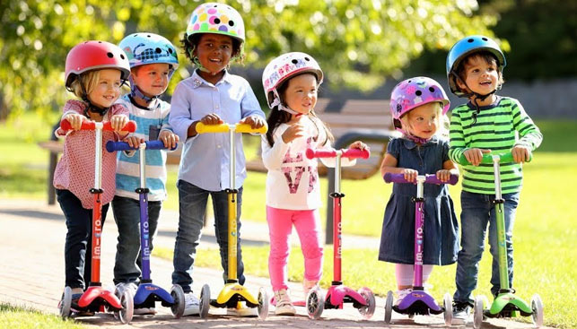 bonus monopattino - dei bambini in fila con il casco in testa e tutti su un monopattino