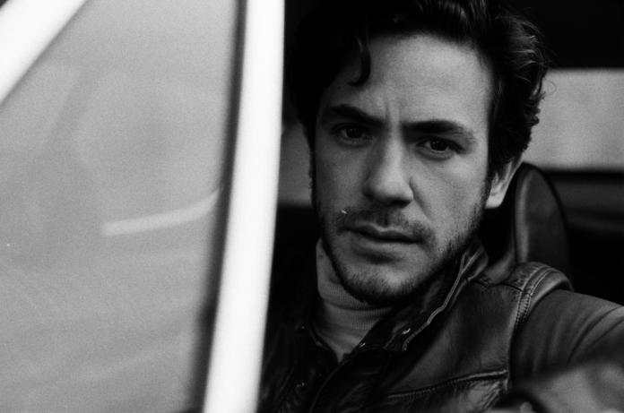 In foto il cantante Jack Savoretti, foto in bianco e nero, si affaccia al finestrino dell'auto e guarda in camera