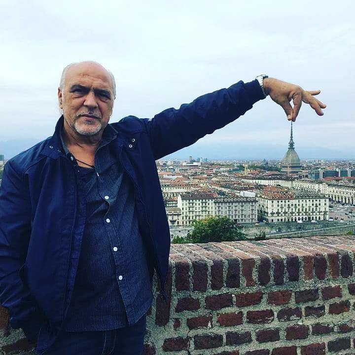 #CabaretShow - Pippo Romano con sullo sfondo la città di Torino lui tiene tra le dita la punta della Mole Antonelliana