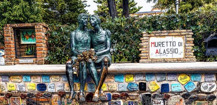 Alassio il muretto con le piastrelle firmate da personaggi famosi e una statua di una coppia che si abbraccia