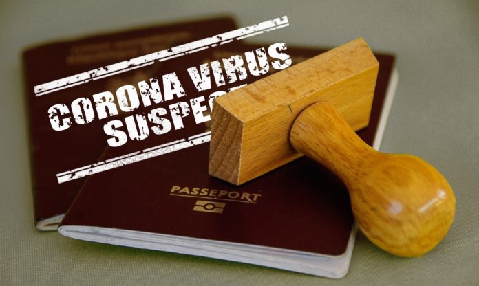 Covid 19 e trasmissione - nella foto due passaporti, un timbro e la scritta corona virus suspected