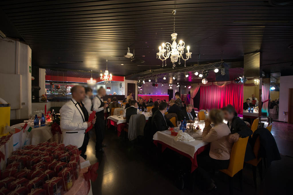 Il Palcoscenico Piccolo Teatro - il locale con i tavoli tanta gente seduta che mangia e i camerieri. Sullo sfondo il palco con un sipario rosso