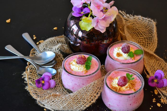 Salone del gusto - tre coppete di vetro con della mousse di frutta e delle fragole come guarnizione, un vaso con dei fiorellini e dei cucchiaini