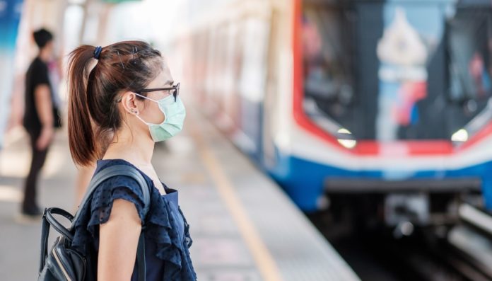 parcheggi gratuiti - una ragazza con mascherina in attesa sul binario di un treno