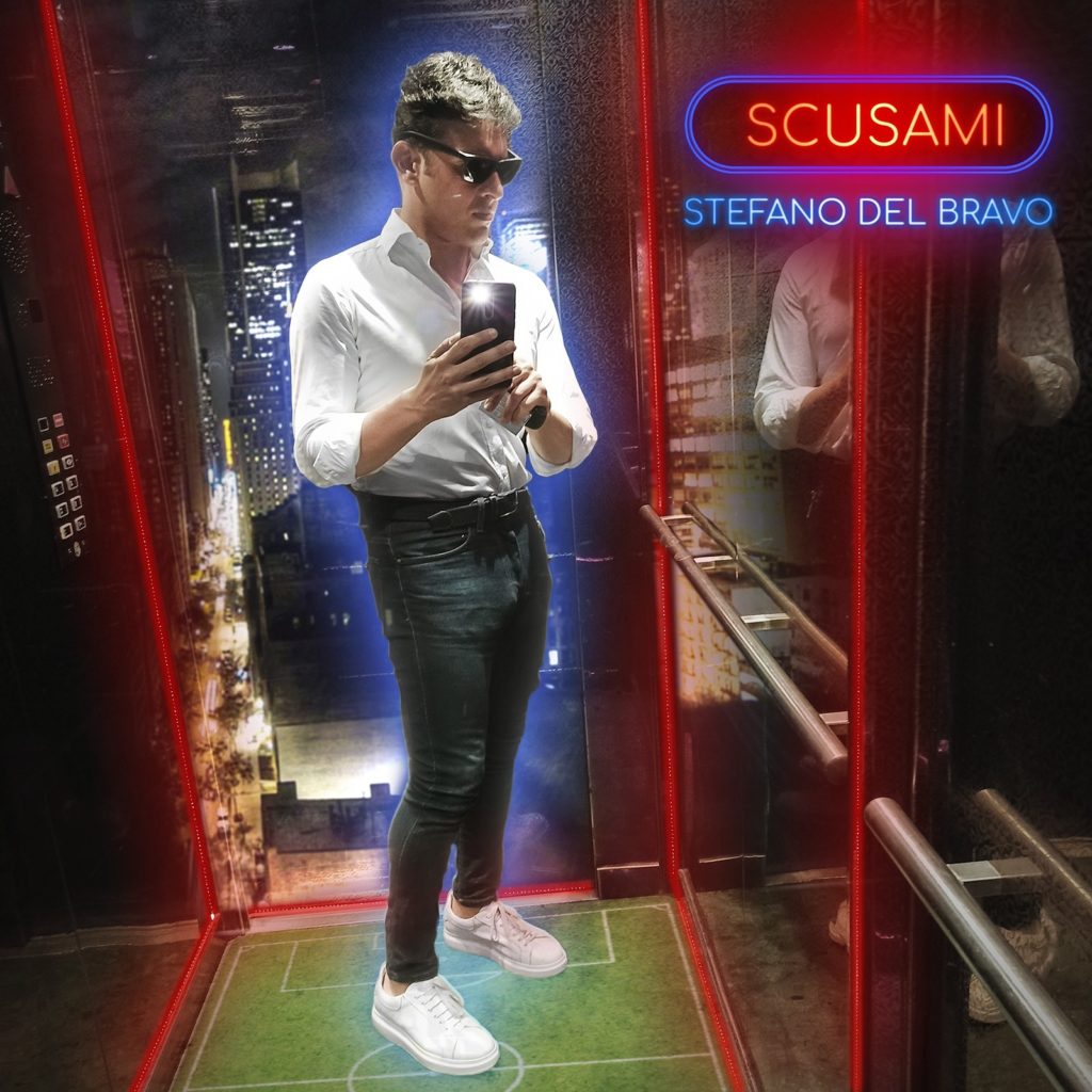 stefano del bravo - la copertina di scusami - il cantante, pantaloni neri e camicia bianca, occhiali da sole e telefonino in mano