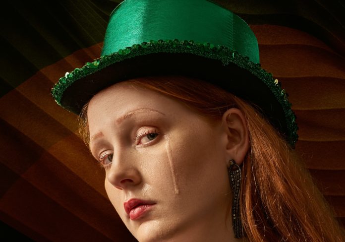 Presidente - Nella foto un'artista donna con cappello verde con aguardo triste piange