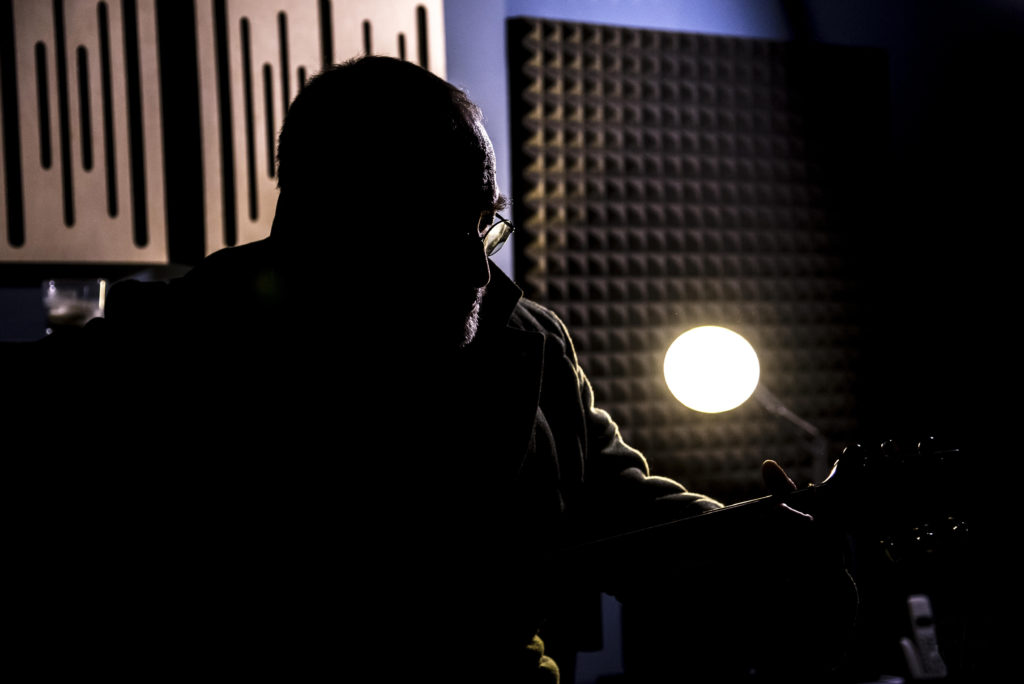 pietre giors - il cantautere torinese, in controluce, in uno studio di regisrazione, mentre suona la chitarra