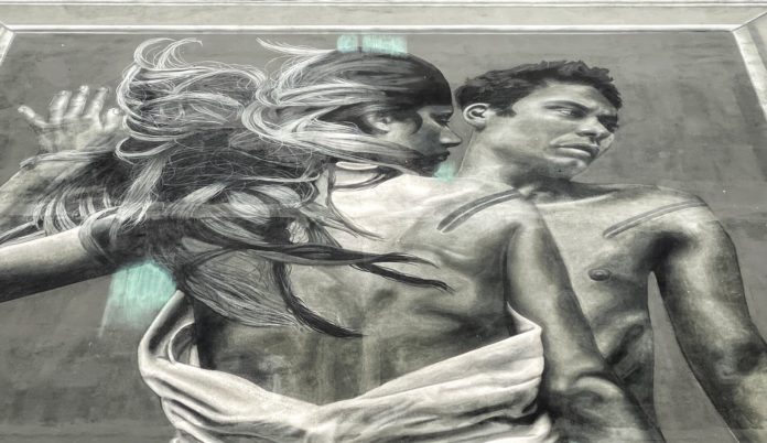 Outside In un particolare del murales in bianco e nero con un uomo e una donna abbracciati