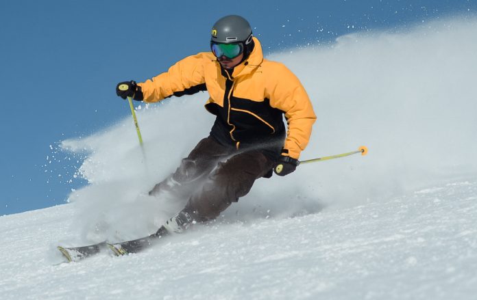 piste da sci con uno sciatore con tuta gialla che scia